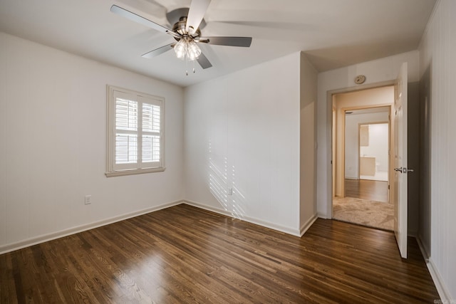 unfurnished room featuring dark wood-style flooring, a ceiling fan, and baseboards