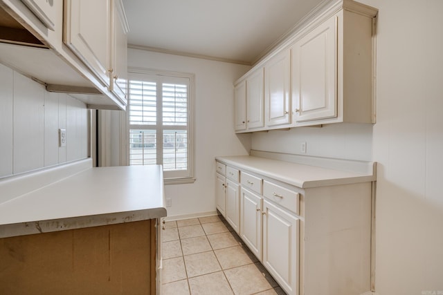 kitchen with light countertops, white cabinets, crown molding, and light tile patterned floors