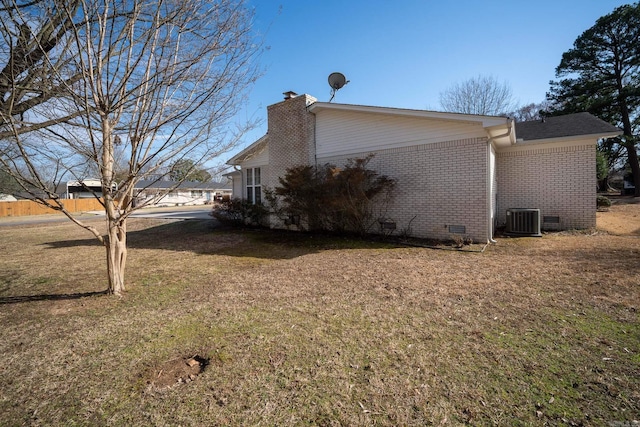 view of home's exterior with central AC unit, brick siding, a yard, crawl space, and a chimney