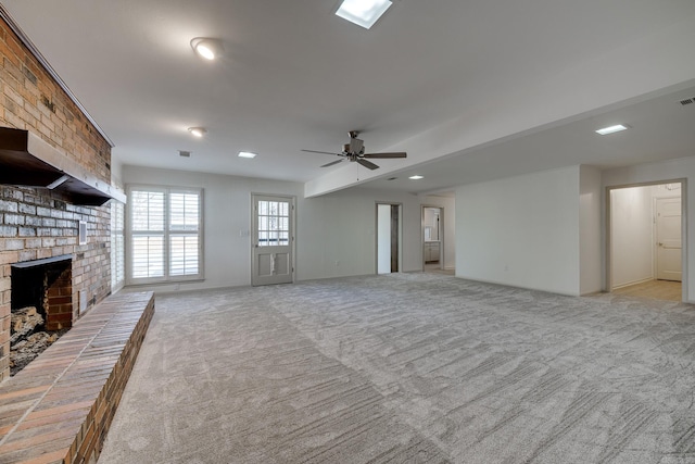 unfurnished living room with ceiling fan, a fireplace, visible vents, and light colored carpet