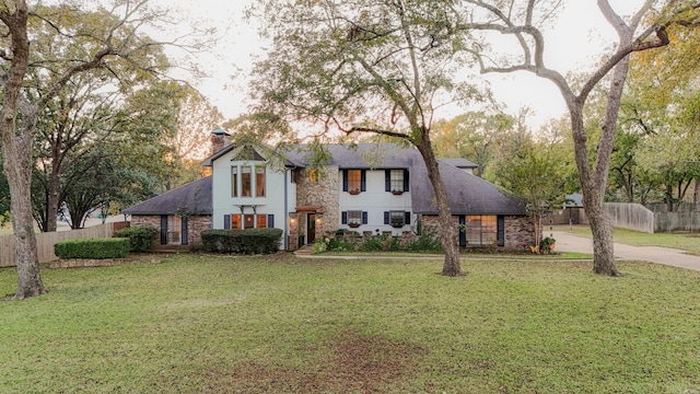 view of front of property featuring a chimney, fence, and a front lawn