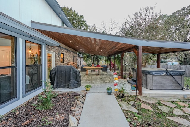 view of patio / terrace with area for grilling, fence, and a hot tub