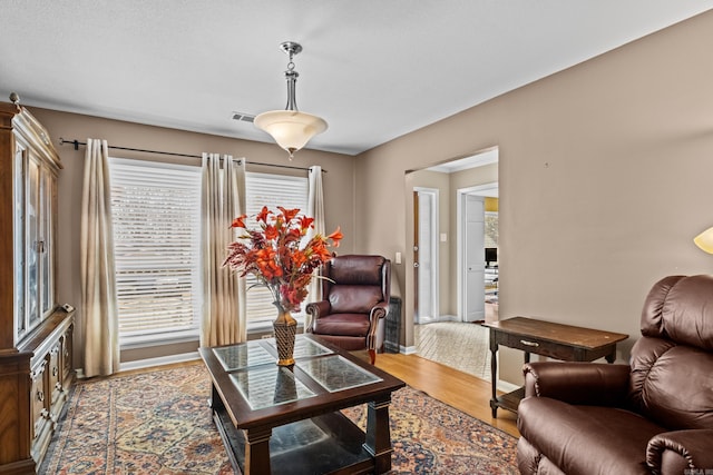 living area with visible vents, baseboards, and wood finished floors