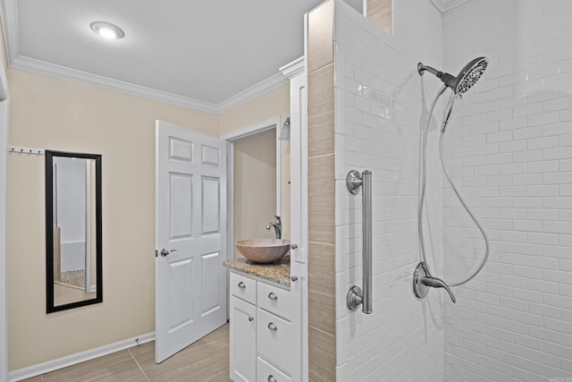 full bathroom featuring baseboards, crown molding, a tile shower, and vanity