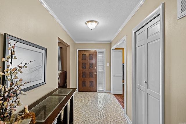 entryway featuring baseboards, ornamental molding, and a textured ceiling