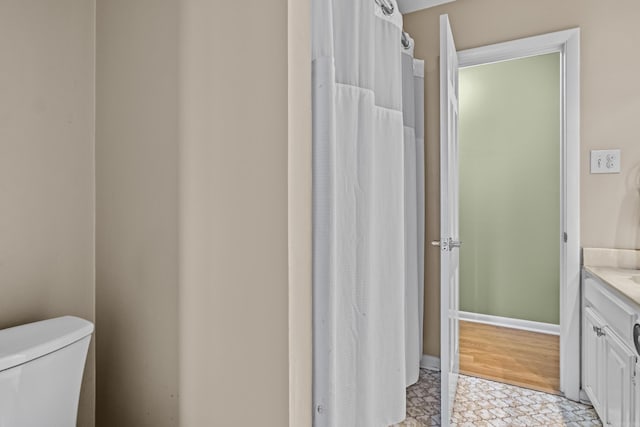 bathroom with toilet, tile patterned floors, baseboards, and vanity