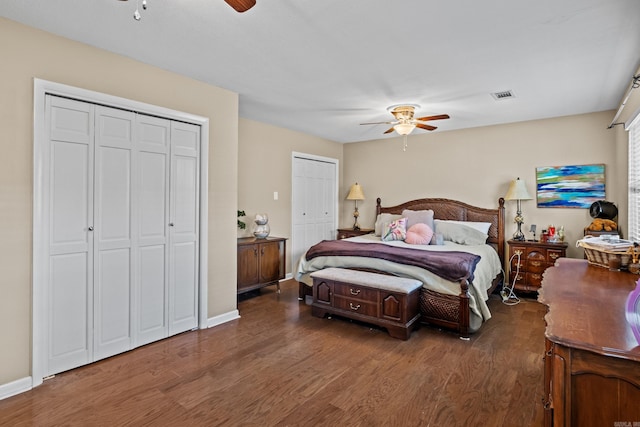 bedroom featuring multiple closets, ceiling fan, visible vents, and wood finished floors