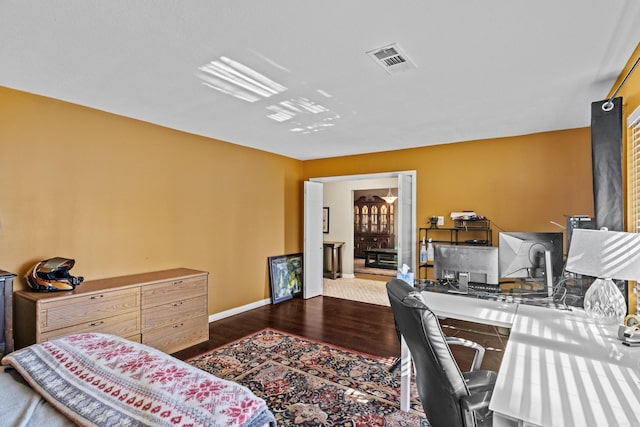 home office featuring wood finished floors, visible vents, and baseboards