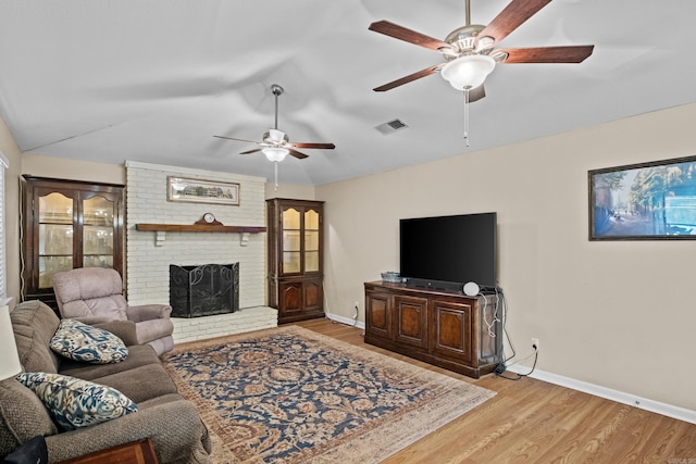 living room with visible vents, baseboards, vaulted ceiling, a brick fireplace, and light wood-type flooring