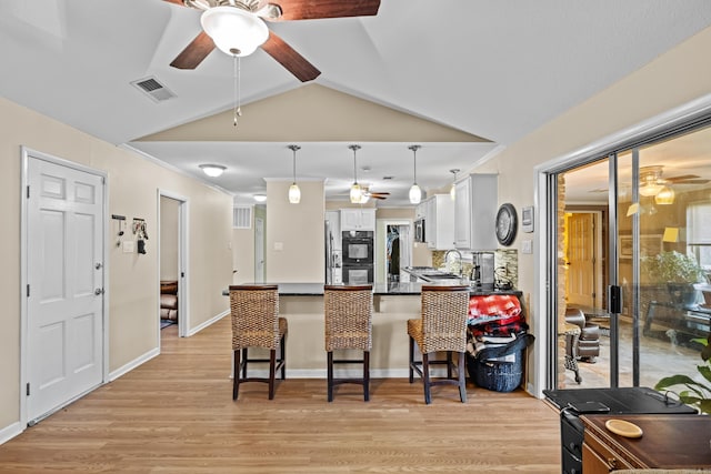 kitchen featuring dark countertops, visible vents, dobule oven black, white cabinetry, and a peninsula