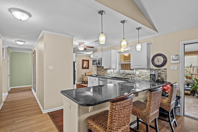 kitchen with appliances with stainless steel finishes, a sink, a breakfast bar, and tasteful backsplash