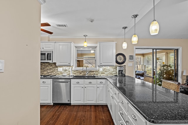 kitchen with visible vents, dark wood-type flooring, a peninsula, stainless steel appliances, and a sink