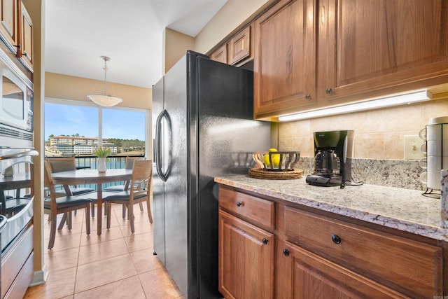 101 Long Island Dr Unit 202, Hot Springs National Park, AR 71913 - kitchen featuring light tile patterned flooring, backsplash, freestanding refrigerator, light stone countertops, and brown cabinets