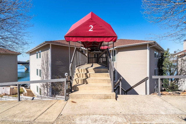 view of front facade featuring a shingled roof and a water view