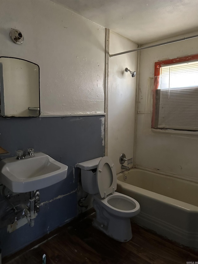 bathroom featuring a sink, bathing tub / shower combination, toilet, and wood finished floors