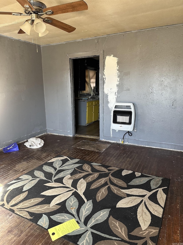 spare room with heating unit, baseboards, and wood finished floors