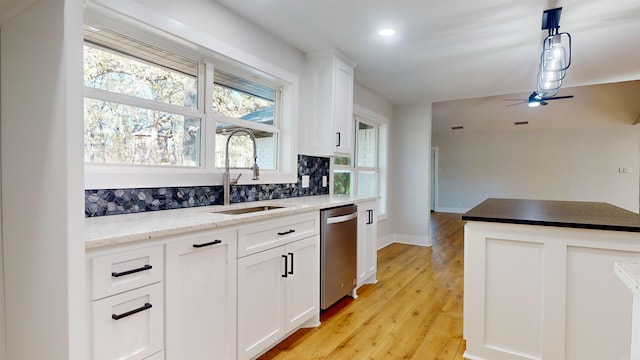 kitchen featuring white cabinets, dishwasher, light wood-style flooring, decorative light fixtures, and a sink