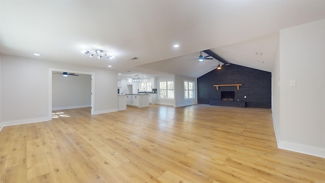 unfurnished living room featuring vaulted ceiling with beams, light wood finished floors, ceiling fan, and a fireplace