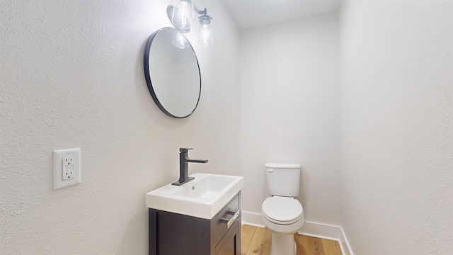 bathroom with toilet, baseboards, wood finished floors, and vanity