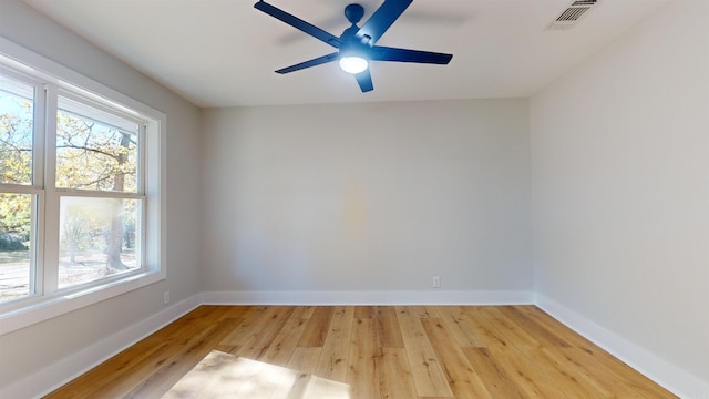 empty room featuring a ceiling fan, light wood-type flooring, visible vents, and baseboards