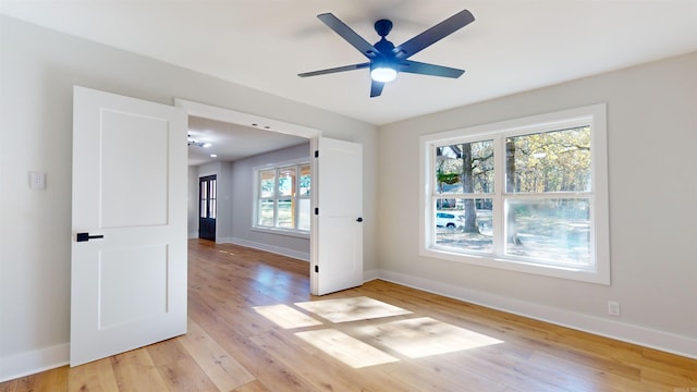 spare room featuring ceiling fan, light wood finished floors, and baseboards