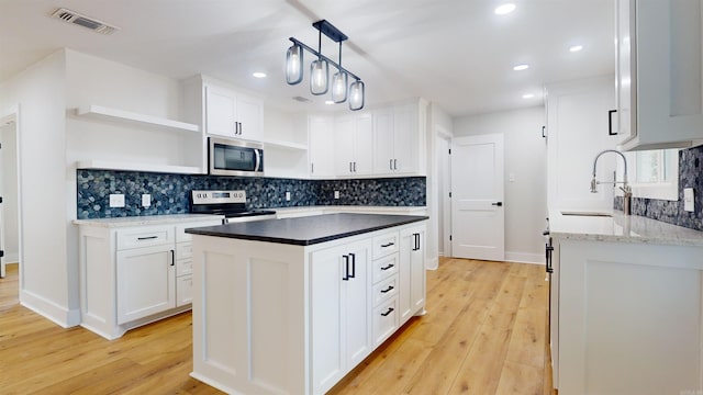 kitchen with light wood finished floors, visible vents, appliances with stainless steel finishes, open shelves, and a sink