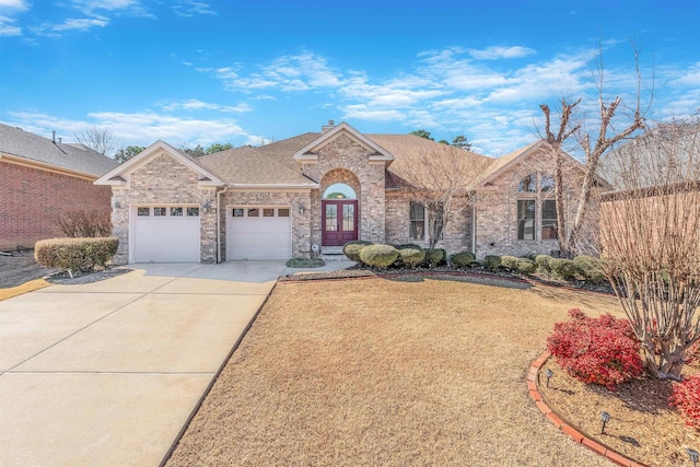 view of front of house featuring a garage, driveway, brick siding, and roof with shingles