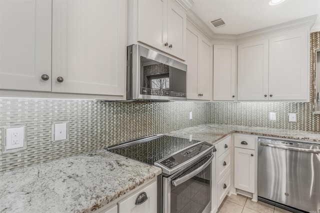 kitchen featuring light tile patterned floors, stainless steel appliances, tasteful backsplash, and white cabinets