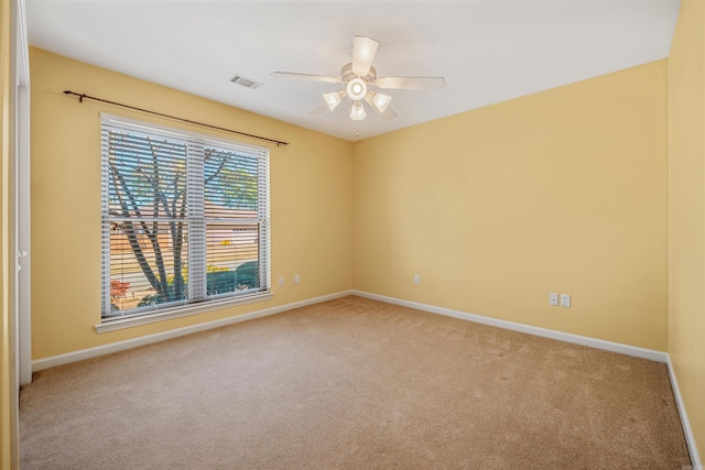 carpeted spare room with a ceiling fan, visible vents, and baseboards