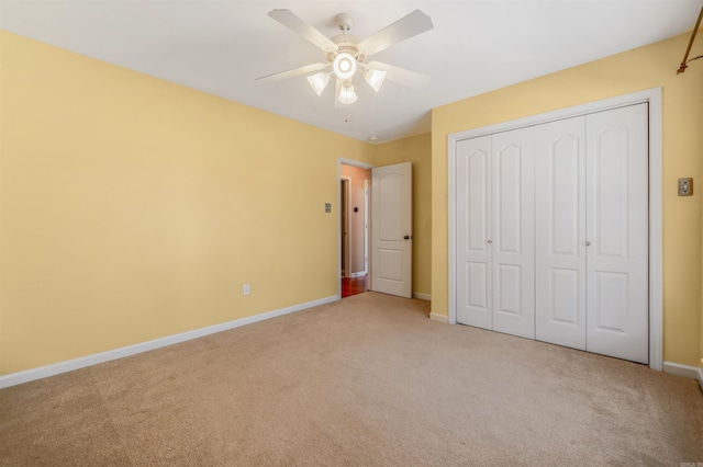 unfurnished bedroom featuring light carpet, a ceiling fan, baseboards, and a closet