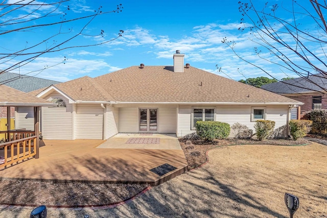 rear view of property featuring a shingled roof, a chimney, and a wooden deck