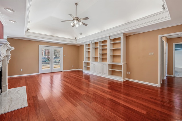 unfurnished living room with hardwood / wood-style floors, a raised ceiling, french doors, and a stone fireplace