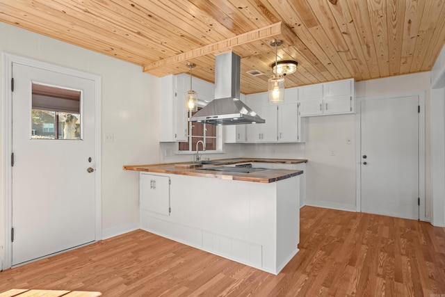 kitchen with a peninsula, a sink, wood ceiling, light wood finished floors, and island exhaust hood