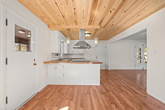 kitchen with island range hood, a peninsula, a sink, wood ceiling, and light wood-style floors