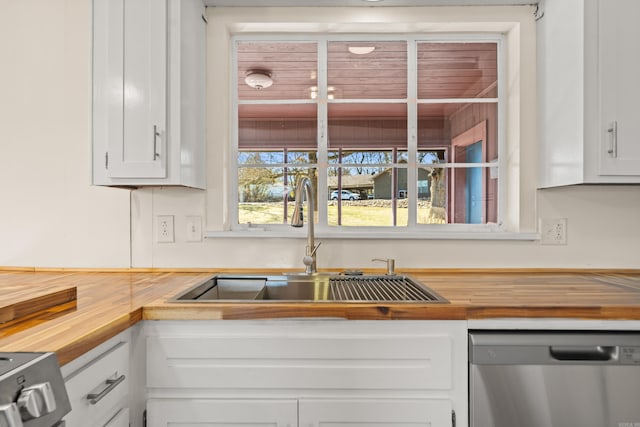 kitchen featuring a sink, white cabinetry, stainless steel appliances, and wooden counters