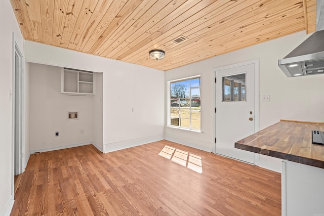 unfurnished dining area featuring wooden ceiling, baseboards, and wood finished floors