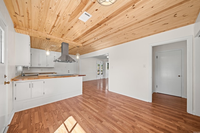 kitchen with island range hood, a sink, visible vents, wooden counters, and light wood finished floors