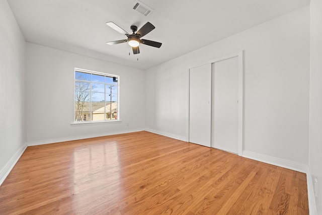 unfurnished bedroom with baseboards, a closet, visible vents, and wood finished floors