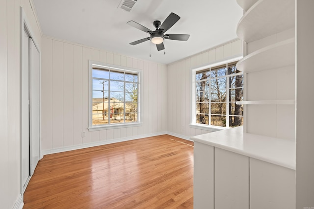 interior space featuring light wood finished floors, ceiling fan, visible vents, and baseboards