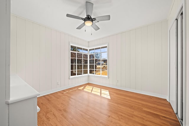 spare room with light wood-type flooring, ceiling fan, and baseboards