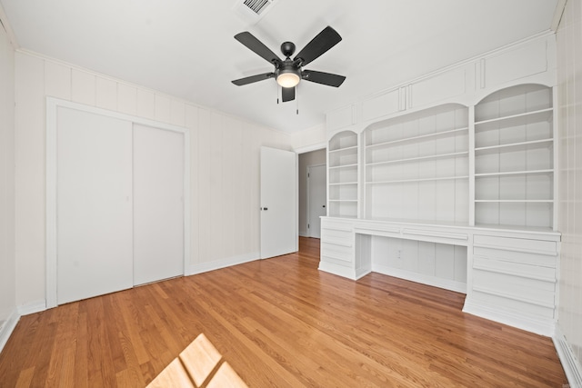 unfurnished bedroom with a closet, wood finished floors, visible vents, and a ceiling fan