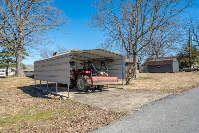 view of car parking with driveway, a shed, and a detached carport