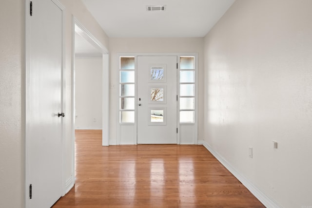 foyer featuring light wood finished floors, baseboards, and visible vents