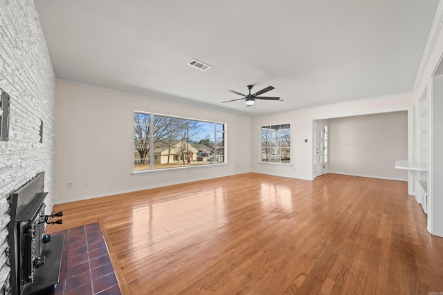 unfurnished living room with a fireplace, wood finished floors, visible vents, baseboards, and a ceiling fan