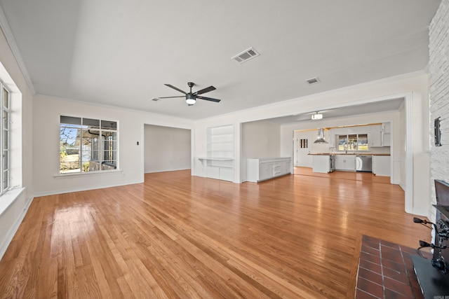 unfurnished living room with light wood-style floors, a fireplace, visible vents, and a ceiling fan