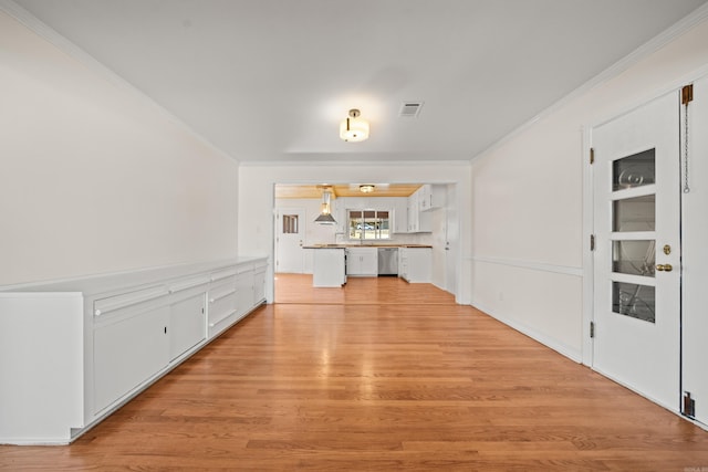 interior space with light wood-style flooring, visible vents, and crown molding