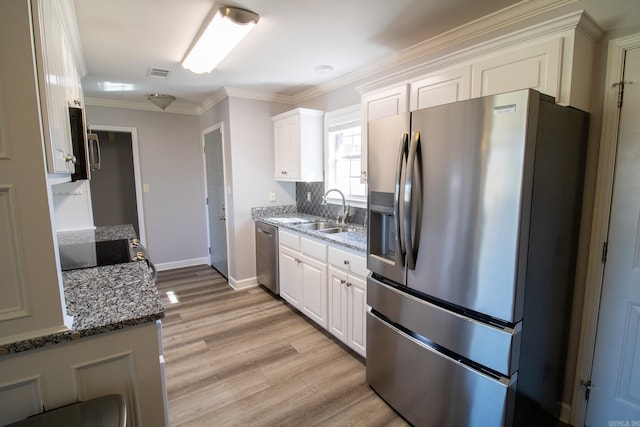 kitchen with light wood finished floors, visible vents, stainless steel appliances, crown molding, and a sink