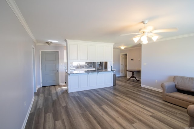 kitchen with ornamental molding, open floor plan, white cabinetry, and a sink