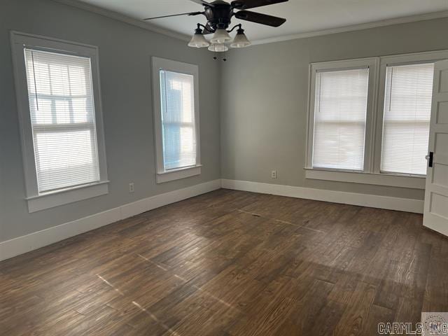 spare room featuring ceiling fan, baseboards, dark wood-type flooring, and crown molding