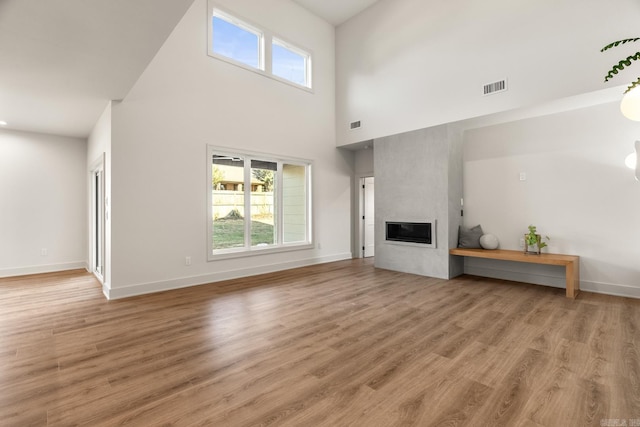 unfurnished living room featuring light wood finished floors, plenty of natural light, a fireplace, and visible vents